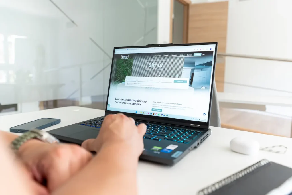 Persona usando portátil con la página web de Simur Spaces abierta en una oficina moderna en Málaga.