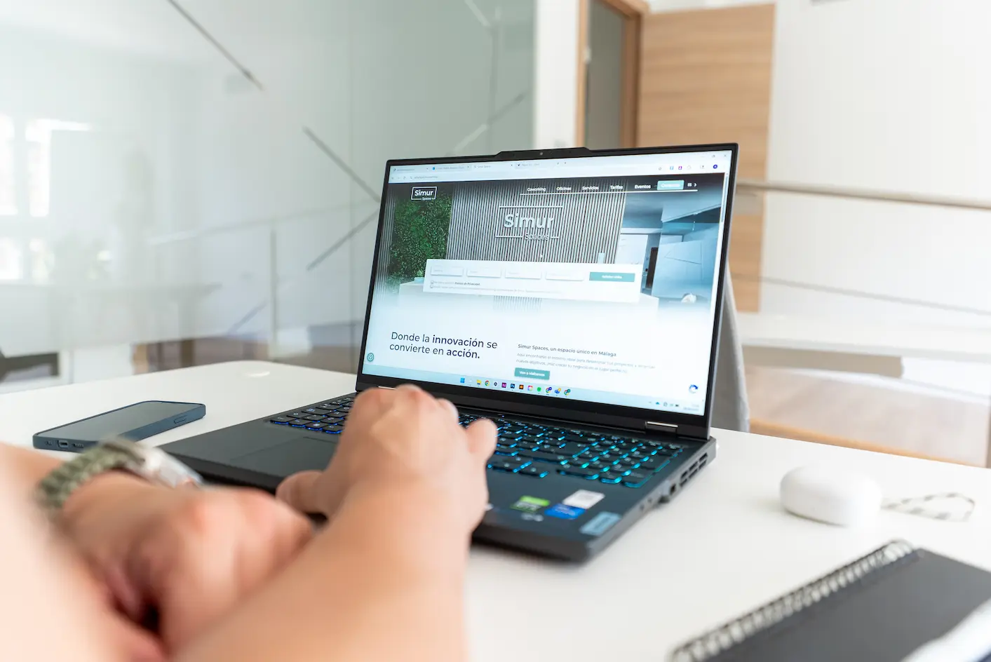 Persona usando portátil con la página web de Simur Spaces abierta en una oficina moderna en Málaga.